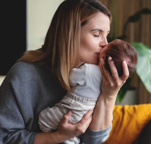 Loving Mother Hugs Her Little Baby At Home
